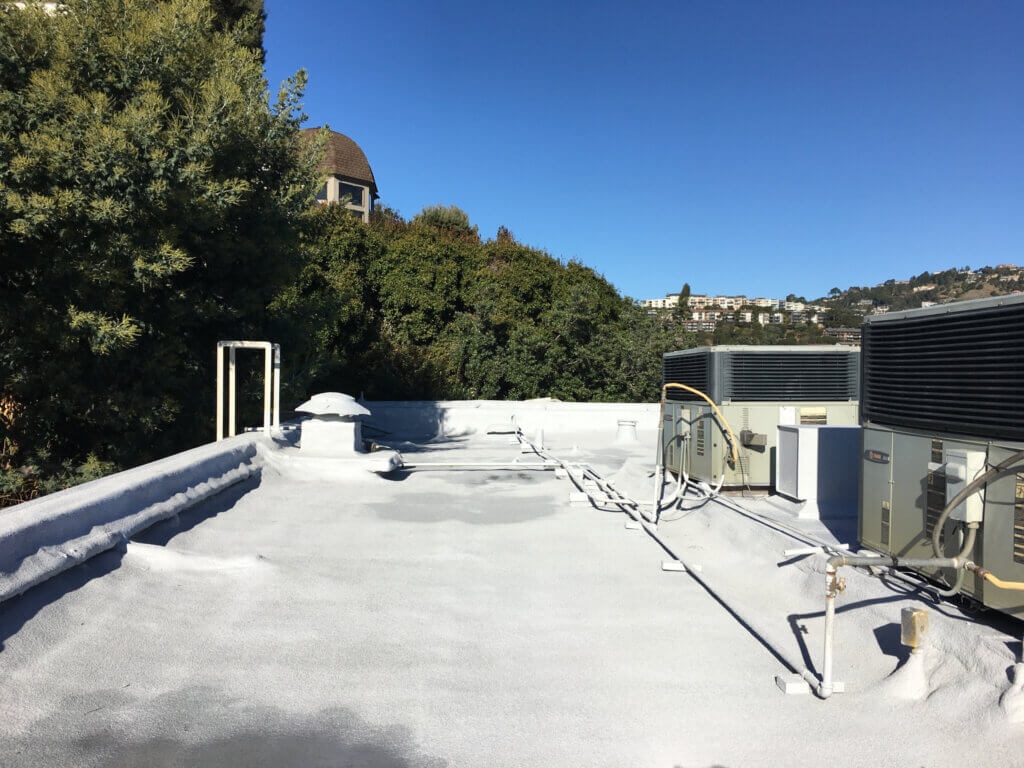 Foam roofing for multi-story building with HVAC systems installed on the roof