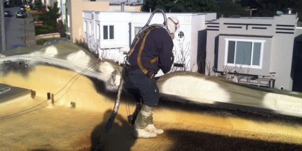 Armstrong Roofing - spf installer spraying the edges of a flat roof