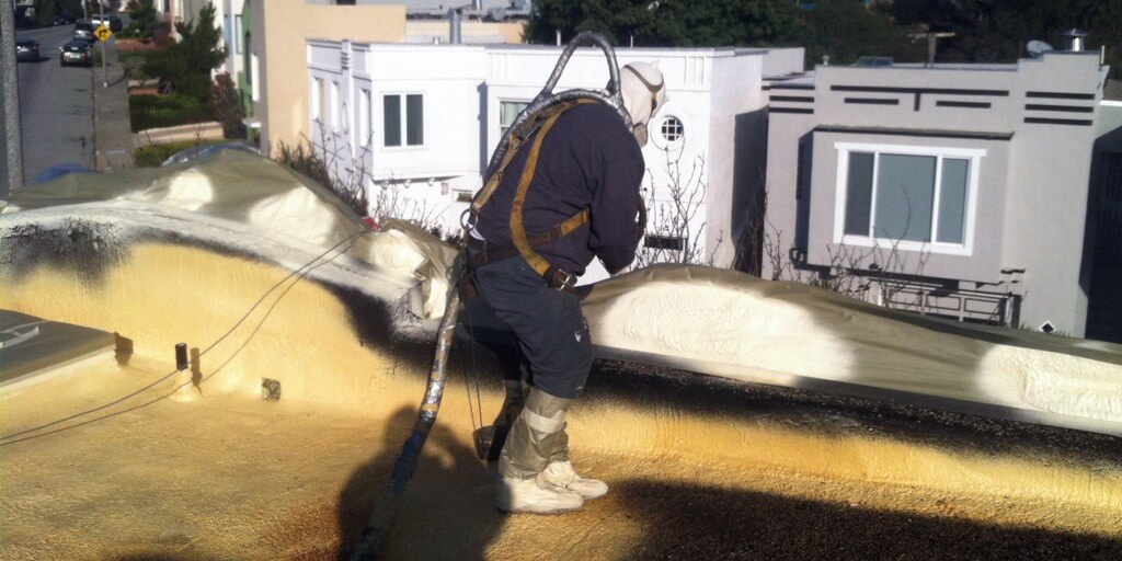 Armstrong Roofing - spf installer spraying the edges of a flat roof