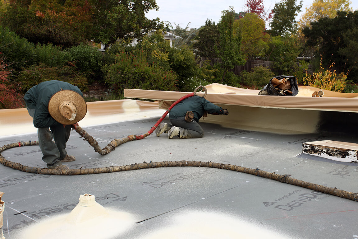 Armstrong Foam Roofing - two men on a flat roof installing foam roofing