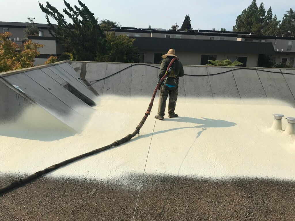 a technician spraying foam roofing on a flat Bay Area roof